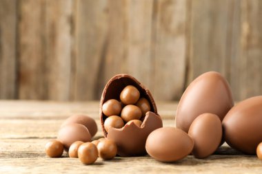 Mutlu Paskalyalar. Ahşap masada şekerli çikolatalı yumurtalar, yakın plan. Metin için boşluk