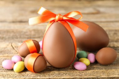 Ahşap masada renkli şekerlemeli lezzetli çikolata yumurtaları, yakın plan. Mutlu Paskalyalar