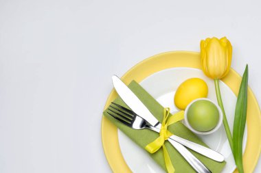 Paskalya kutlaması. Lale çiçekli şenlik masası ve beyaz arka planda boyanmış yumurtalar, üst manzara. Metin için boşluk