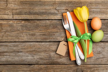 Paskalya sofrası. Lale ve ahşap arka planda boyanmış yumurtaları olan güzel gümüş takımlar, üst manzara. Metin için boşluk