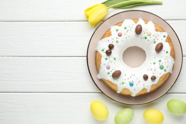 Lezzetli Paskalya pastası, beyaz ahşap masa üzerinde boyanmış yumurta ve lale çiçeği, düz yatak. Metin için boşluk