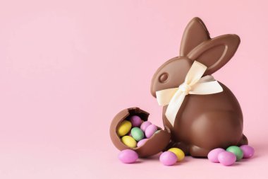 Çikolatalı Paskalya tavşanı ve pembe arka planda şekerli yumurta. Metin için boşluk