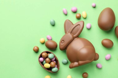 Çikolatalı Paskalya tavşanı ve açık yeşil arka planda yumurtalar. Metin için boşluk