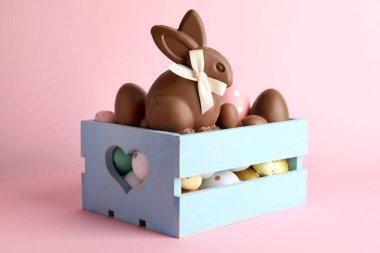Çikolatalı Paskalya tavşanı ve pembe arka planda yumurtalar, yakın plan.