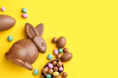 Çikolatalı Paskalya tavşanı ve sarı arka planda yumurtalar, düz yatak. Metin için boşluk