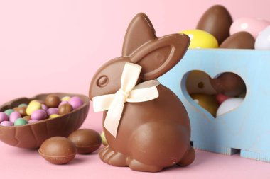 Çikolatalı Paskalya tavşanı ve pembe arka planda yumurtalar, yakın plan.