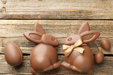 Çikolatalı Paskalya tavşanları ve yumurtalar ahşap masada, düz yerde. Metin için boşluk