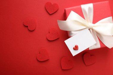 Sevgililer Günün kutlu olsun. Tebrik kartı ve kırmızı arka planda dekoratif kalpleri olan güzel bir hediye. Metin için boşluk