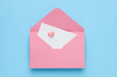 Happy Valentine's day. Envelope with greeting card and decorative heart on light blue background, top view