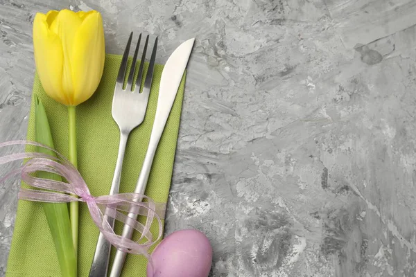 Paskalya sofrası. Güzel gümüş takımlar, lale ve gri arka planda boyanmış yumurta, üst manzara. Metin için boşluk