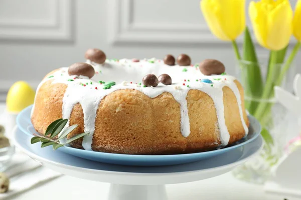 Delicious Easter cake and yellow tulips on table indoors, closeup