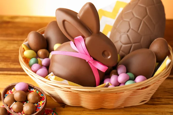 Çikolatalı Paskalya tavşanı hasır sepetin içinde yumurta ve şekerle ahşap masada, yakın plan.