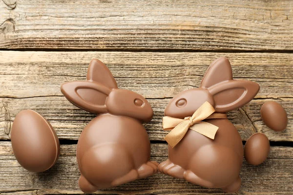 Çikolatalı Paskalya tavşanları ve yumurtalar ahşap masada, düz yerde. Metin için boşluk