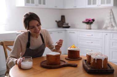 Genç bir kadın geleneksel paskalya pastasını mutfakta jöleli dekore ediyor. Metin için boşluk