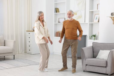 Mutlu yaşlı çift evde dans ediyor.