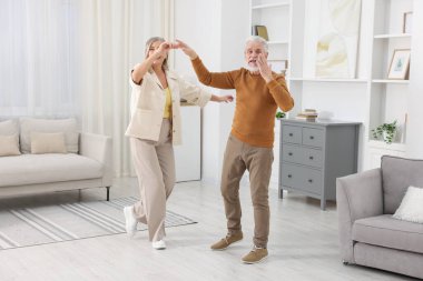 Mutlu yaşlı çift evde dans ediyor.