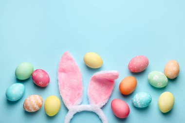 Mutlu Paskalyalar. Şirin tavşan kulakları ve açık mavi arka planda yumurtalar, düz bir şekilde yatıyordu. Metin için boşluk