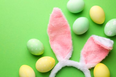 Mutlu Paskalyalar. Şirin tavşan kulakları ve yeşil arka planda boyanmış yumurtalar. Metin için boşluk
