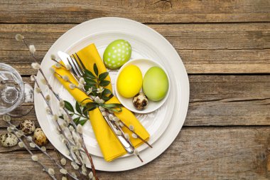 Paskalya yumurtaları ve söğüt dallarıyla ahşap arka planda düzlük.