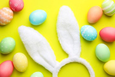 Mutlu Paskalyalar. Sevimli tavşan kulakları ve sarı arka planda boyanmış yumurtalar.