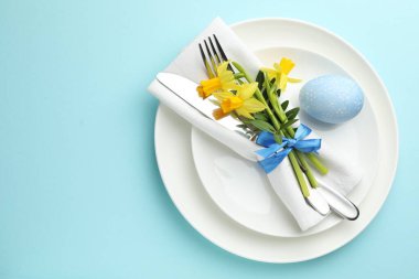 Paskalya kutlaması. Nergis çiçekleri ve açık mavi arkaplan üzerine boyanmış yumurta içeren şölen masası, üst manzara. Metin için boşluk