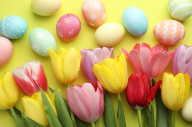 Boyalı Paskalya yumurtaları ve açık yeşil arka planda güzel laleler.