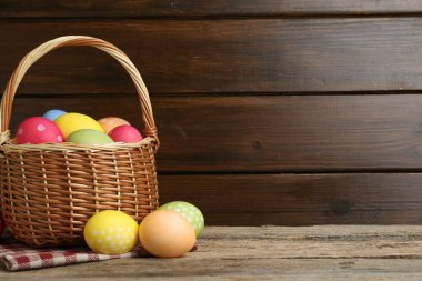 Tahta masadaki hasır sepete boyanmış Paskalya yumurtaları. Metin için boşluk
