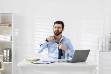 Beyaz duvarın yanındaki masada sıcaktan muzdarip bir adam var.