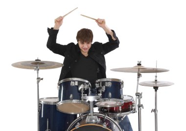 Elinde bagetlerle gülümseyen genç çocuk beyaz arka planda davul çalmayı öğreniyor.