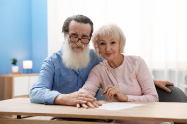 Ahşap masada son arzuları ve vasiyetnameleri imzalayan yaşlı çift.