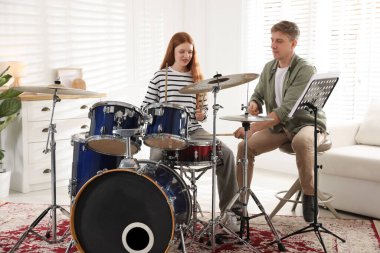 Genç kız içeride müzik öğretmeniyle bateri çalmayı öğreniyor.