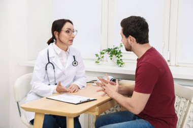 Klinikteki ahşap masada pano danışmanı olan bir doktor.