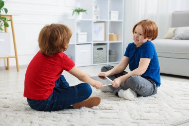 Evde tablet üzerinde kavga eden iki kardeş.