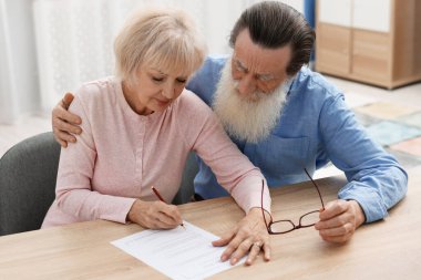 Ahşap masada son arzuları ve vasiyetnameleri imzalayan yaşlı çift.