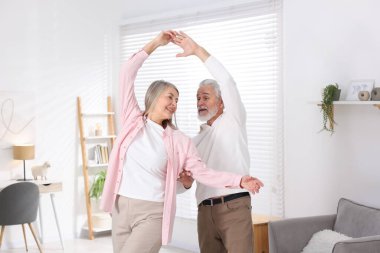 Mutlu yaşlı çift evde dans ediyor.