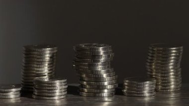 Gri arka plana karşı ahşap masada yığınla bozuk para, yakın plan. Işığın yönü değiştiriliyor