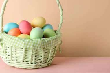 Güzel Paskalya yumurtaları pembe ahşap masada bej arka planda, yakın plan. Metin için boşluk