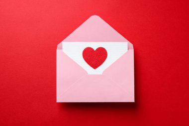 Sevgililer Günün kutlu olsun. Tebrik kartı ve kırmızı arka planda dekoratif kalp ile zarf, üst görünüm