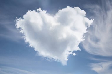 Mavi gökyüzünde sevimli yumuşak kalp şeklinde bulut