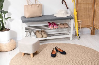 Farklı ayakkabılar, aksesuarlar ve beyaz duvarın yanındaki ev bitkilerinden oluşan ayakkabı deposu.