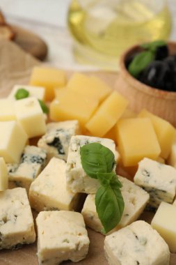 Masada değişik peynir, zeytin ve fesleğen çeşitleri olan servis masası, yakın plan.