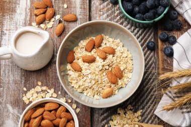 Yulaf gevreği, fındık, badem sütü ve yaban mersini ahşap masada, düz uzanmış