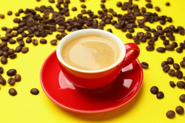 Sarı arka planda aromatik kahve ve fasulye bardağı, yakın plan.