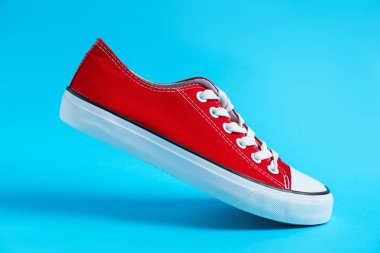 Açık mavi arka planda şık bir spor ayakkabı, yakın plan.