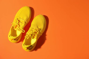 Turuncu arka planda şık bir çift spor ayakkabı, üst manzara. Metin için boşluk
