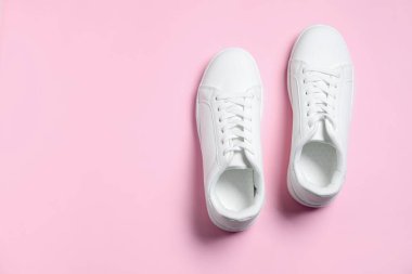 Pembe arka planda şık bir çift spor ayakkabı, üst manzara. Metin için boşluk