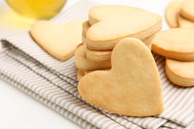 Lezzetli kalp şeklinde tereyağlı kurabiye ve çay beyaz masada, yakın plan.