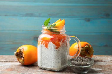 Ahşap masada servis edilen mason kavanozunda hurma ve nane aromalı lezzetli chia pudingi.