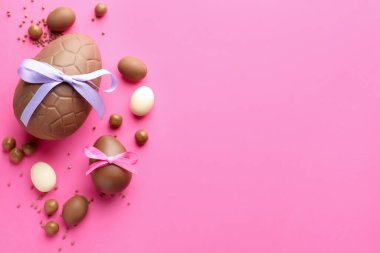 Pembe arka planda şekerli, çikolatalı Paskalya yumurtaları. Metin için boşluk