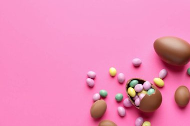 Pembe arka planda şekerli, çikolatalı Paskalya yumurtaları. Metin için boşluk
